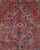 Close-up of the navy and ivory stepped medallion at the center of this red Persian rug