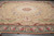 Taupe and gold Aubusson rug photographed indoors showing rosette medallion, ribbon garland and soft fold lines