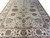 12 x 15 ivory Oushak rug seen at an angle, wide floral border and vine field
