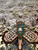 Low angle across pale beige field toward teal pendant and green center medallion