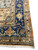 Corner detail of the navy border with coral rosettes, gold outer band and hand-tied fringe