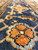 Detail of a 4 petal coral rosette resting on the deep indigo main border