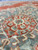 Close-up of wool pile showing sage and coral floral tracery inside the central medallion
