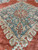 Sage blue medallion filled with rosettes, vines and serrated leaves above a warm coral ground
