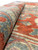 Rolled edge showing wool pile depth, coral and sage coloring, and consistent knotting
