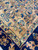 Camel gold main border filled with blue palmettes, coral blossoms and fine ivory guard stripes
