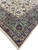 Corner of the beige Kashan rug showing triple border bands and hand-tied ivory fringe