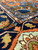 Close-up of thick wool pile where coral border meets navy field with green leaf motifs