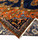 Coral red spandrel and navy corner border meeting the dark blue field with camel vinework