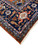 Side corner showing pink guard stripes, rust end finish and ivory fringe on navy Heriz border