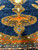 Camel pendant with orange cartouche and cobalt flowers resting on the dark royal blue open field