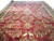 Oversize burgundy Sarouk design rug photographed at an angle showing ivory floral sprays and navy border