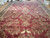 13'6" x 23'6" hand-knotted Indian rug laid on a wood floor, burgundy field with gold botanicals