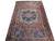 Angled floor view showing brick red field, navy corner spandrels and ivory medallion halo on wool pile