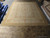12'1" x 15'1" Aubusson flat weave rug laid out on warehouse floor beside rolled rugs