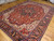 Angled room view of antique hand-knotted Heriz rug showing 8x11 floor scale and geometric drawing
