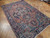 Angled view of the antique Heriz rug showing worn patina, salmon tones and dense wool pile