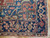 Corner detail showing navy main border, salmon palmettes and ivory zigzag guard stripes on wool