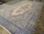 Oversize Persian Kerman rug angled on the floor, ivory ground and pastel floral border