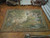 9' x 13'4" tapestry rug laid flat on parquet floor beside rolled and stacked Oriental rugs