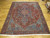 9x12 Persian Heriz rug displayed on hardwood floor, navy medallion centered within a worn rust red field