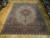 Ivory ground medallion rug seen at an angle showing rust spandrels and deep navy main border