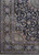 Corner detail showing multiple guard borders, palmettes and scrolling vines against the deep navy field
