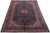 10x13 Persian Kashan rug shown at an angle, navy field, red border, ivory fringe