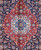 Close-up of red and ivory lobed medallion with sky blue rosette on navy ground