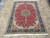 Living room size hand-knotted wool and silk rug with red field and navy floral border