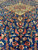 Deep blue field crowded with coral palmettes, olive vines and ivory blossoms below medallion
