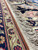 Side cord and ivory guard border detail with hand-tied cotton fringe on palace rug