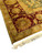 Corner detail showing ivory fringe, olive guard stripe and large rose and gold palmettes