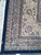 Corner detail showing navy selvage, cotton fringe and multiple floral guard borders in ivory and rose
