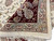 Folded corner revealing the dense hand-knotted back, ivory fringe and berry red border flowers