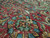 Detail of red border rosette in teal, gold and green wool showing dense antique weave