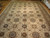 Cream field of 14x24 wool rug showing repeating compartment panels and navy rosette medallions