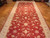 Angled view of hand-knotted wool runner showing palmettes, leafy vines and gold accents