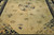 Round Shou medallion and scattered lotus blossoms across the pale beige field of this oversize Peking rug