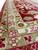 Low angle showing sage green guard border beside red ground with ivory blossoms