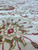 Soft ivory wool pile close-up with pink rosette, olive leaves and red outlines