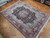 Angled view showing ivory fringe, burgundy border and pale blue spandrels on wool rug