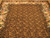 Golden scrolling vine leaves covering the dark brown field of this French style needlepoint area rug