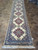 3'4" x 15' Persian Nain runner rug laid out on tile showroom floor with ivory fringe