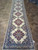 Complete 3'4" x 15' ivory Persian runner photographed full length with navy border and arched end panel