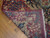Folded back corner revealing tight hand-knotted wool weave, ivory selvage and blue flower border
