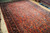 11x16 antique Persian Sarough rug photographed at an angle, dense wool pile and floral sprays