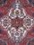 Close-up of ivory octagonal medallion with serrated leaves, rosettes and madder red wool pile