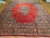 Angled floor view of oversize red Sarouk rug, navy palmette border and salmon guard stripes