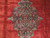 Close-up of hand-knotted floral medallion with navy core, green blue leaves and rose blossoms